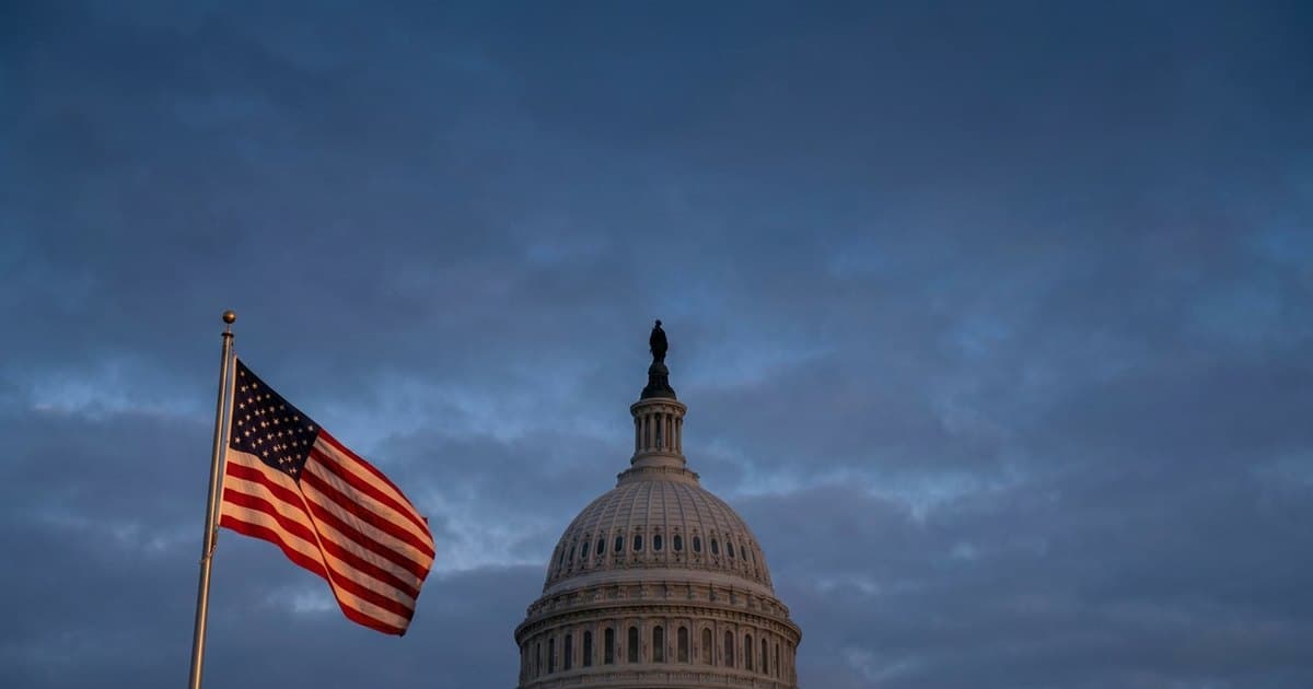 The U.S. Capitol dome at dawn with an American flag