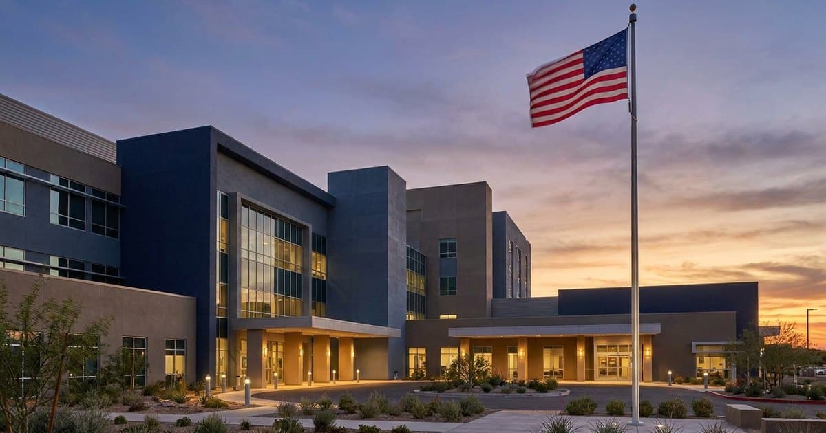 A government hospital building at dusk with an American flag